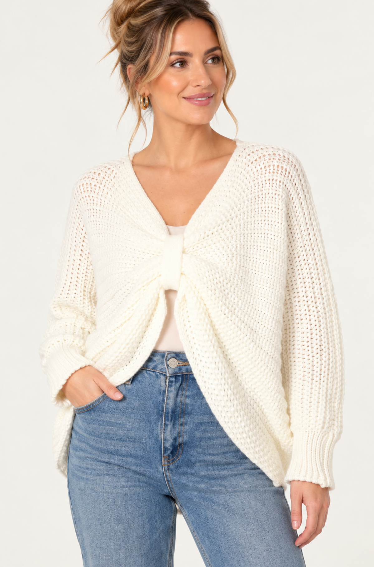 Woman wearing a bow detail chunky knit jumper with two-way reversible twist design and jeans